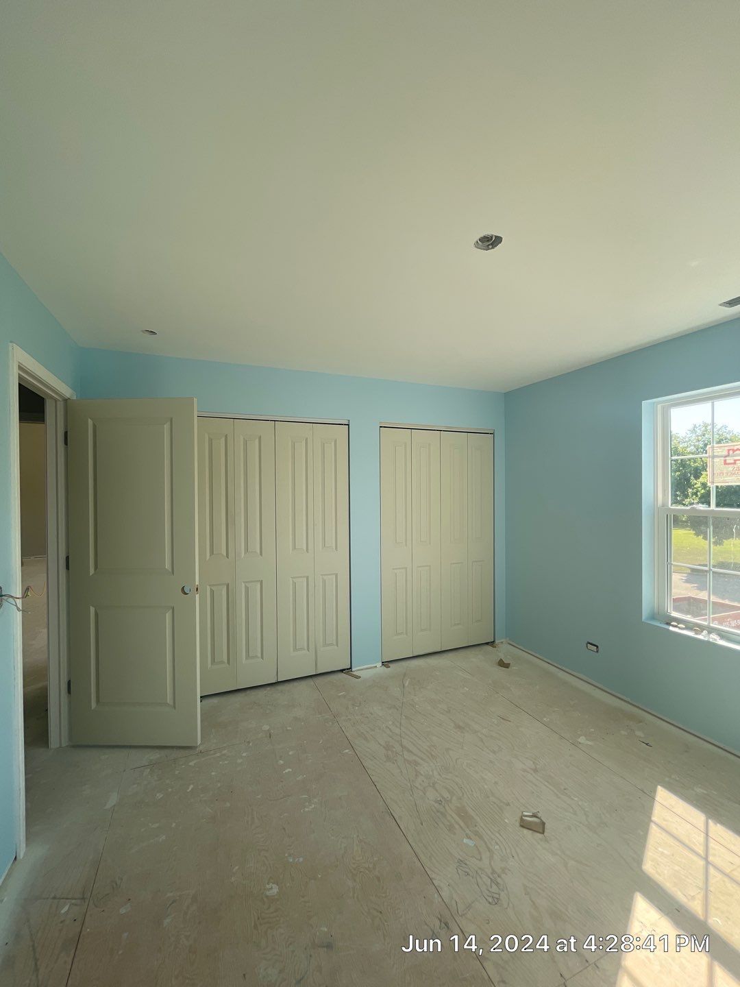 An empty bedroom with blue walls and white doors