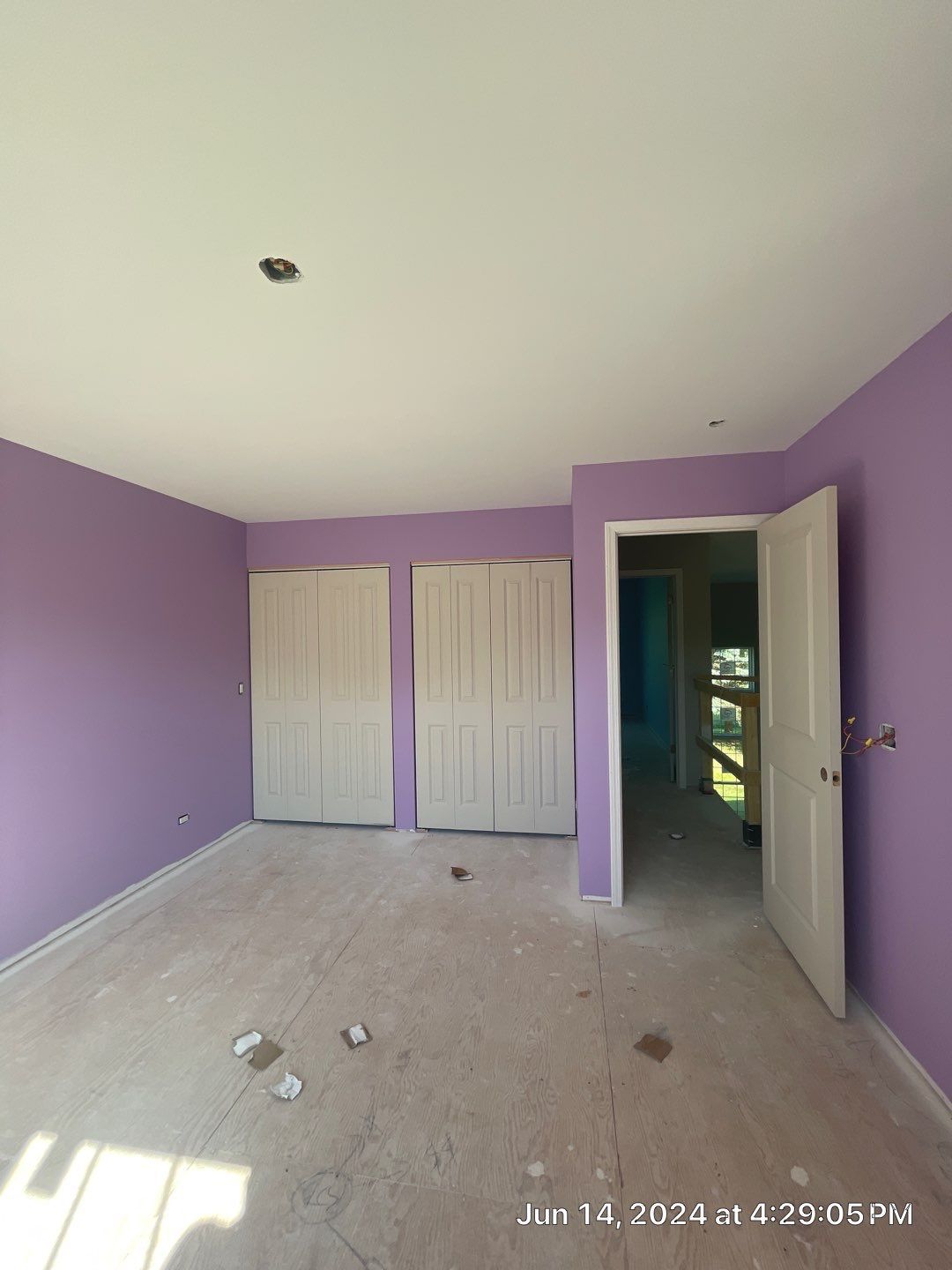 An empty room with purple walls and white doors.