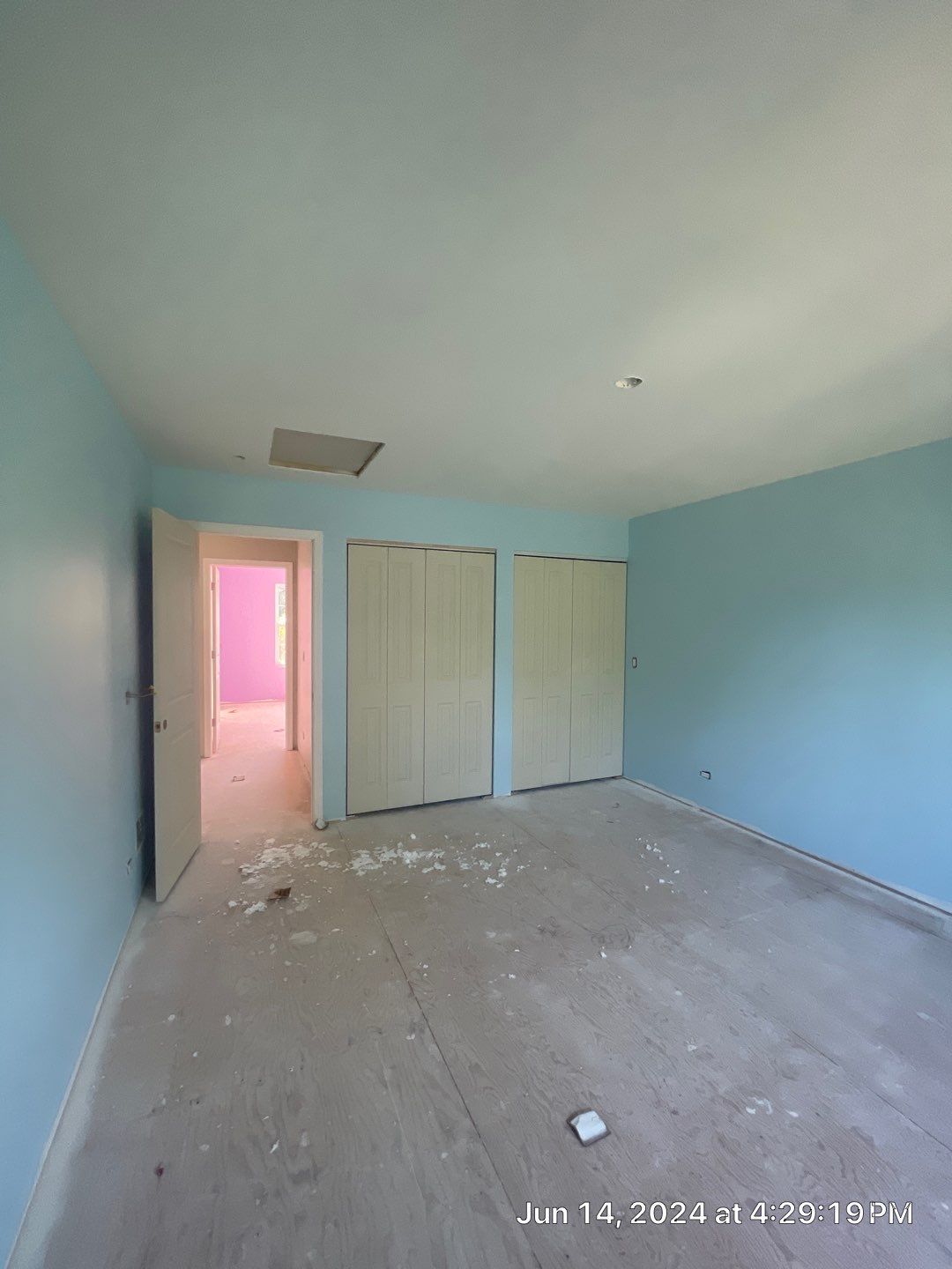 An empty room with blue walls and white closet doors.