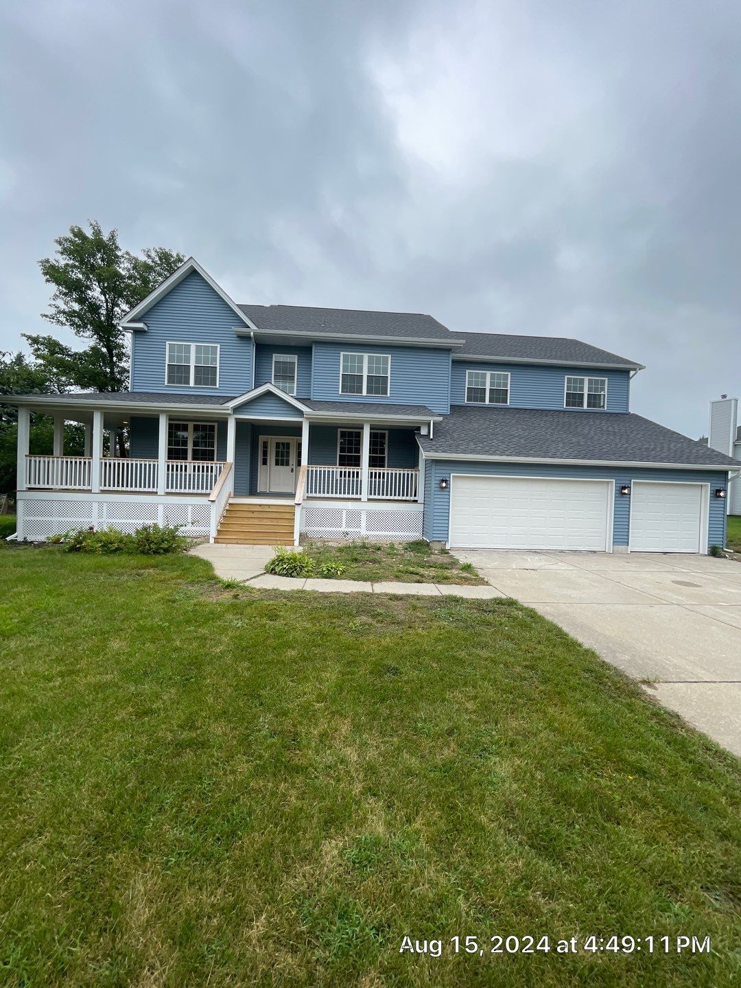 A large blue house with a large porch and a garage.