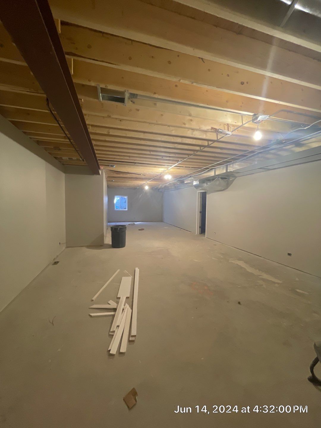 An empty basement with wooden beams and a window.