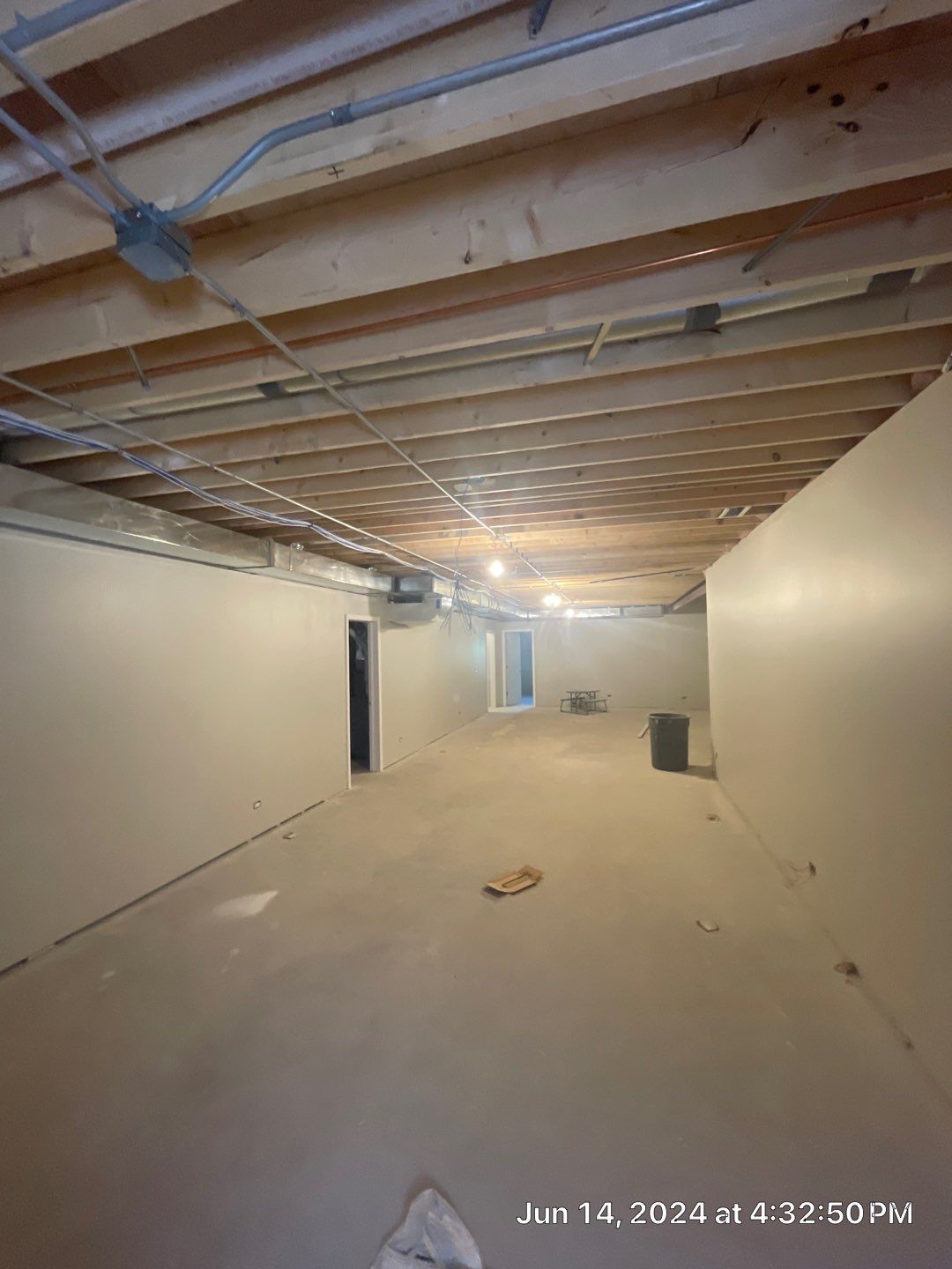 An empty basement with a wooden ceiling and white walls.