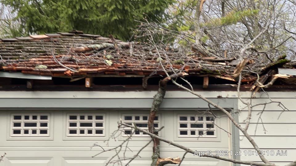 A garage with a roof that has been damaged by a tree.