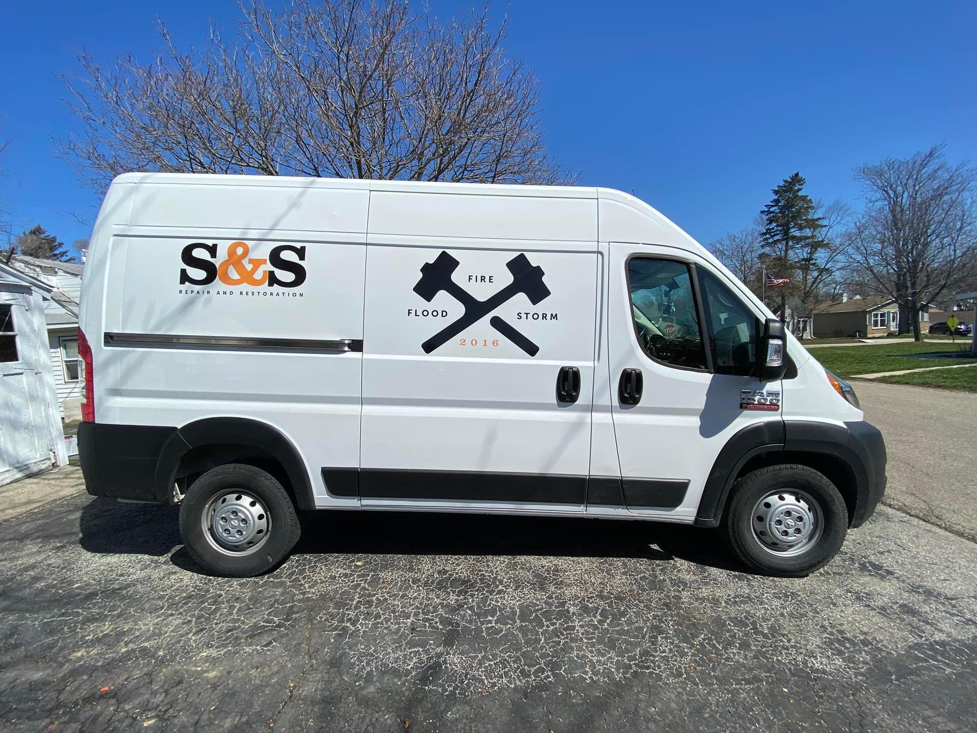 A white van with s & s written on the side is parked in a driveway.