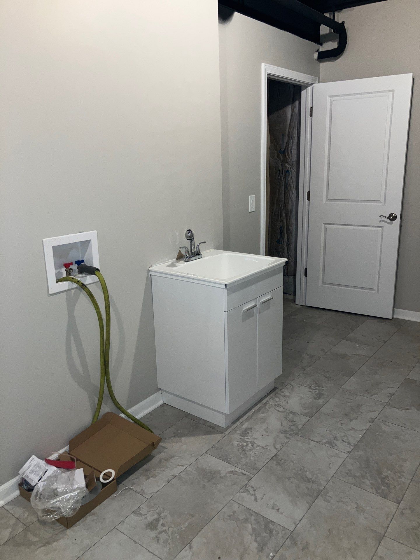 A laundry room with a sink and a box on the floor.