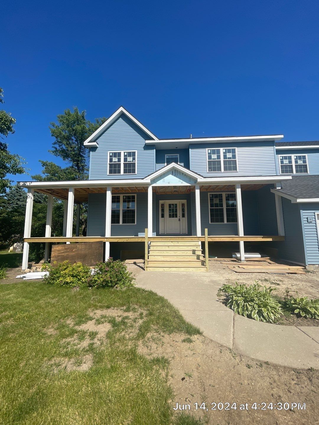 A large blue house with a large porch is being built.