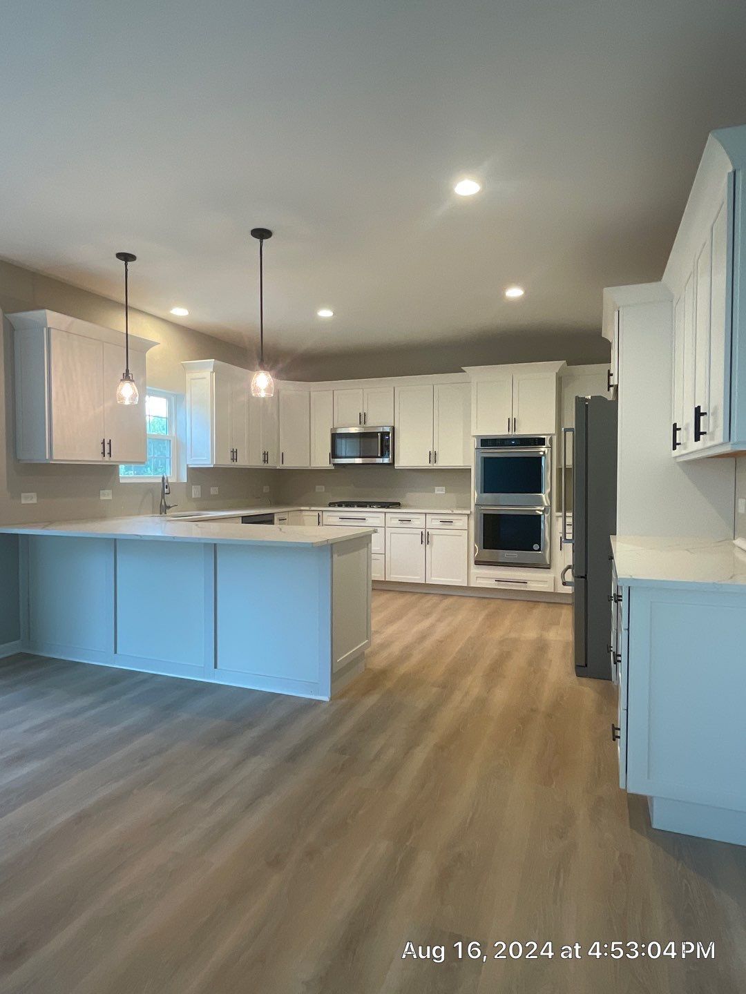 An empty kitchen with white cabinets and wooden floors