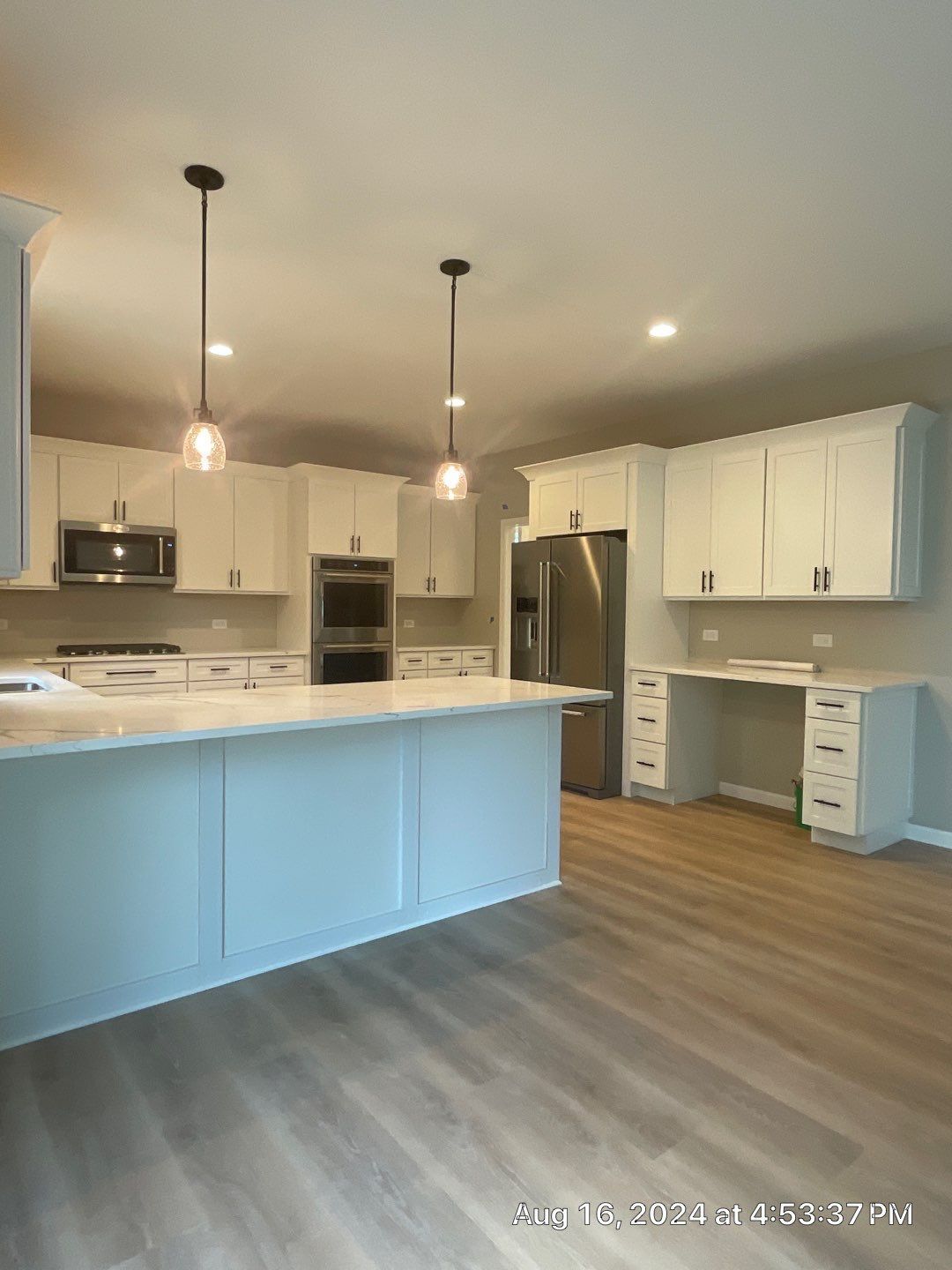 An empty kitchen with white cabinets and a large island