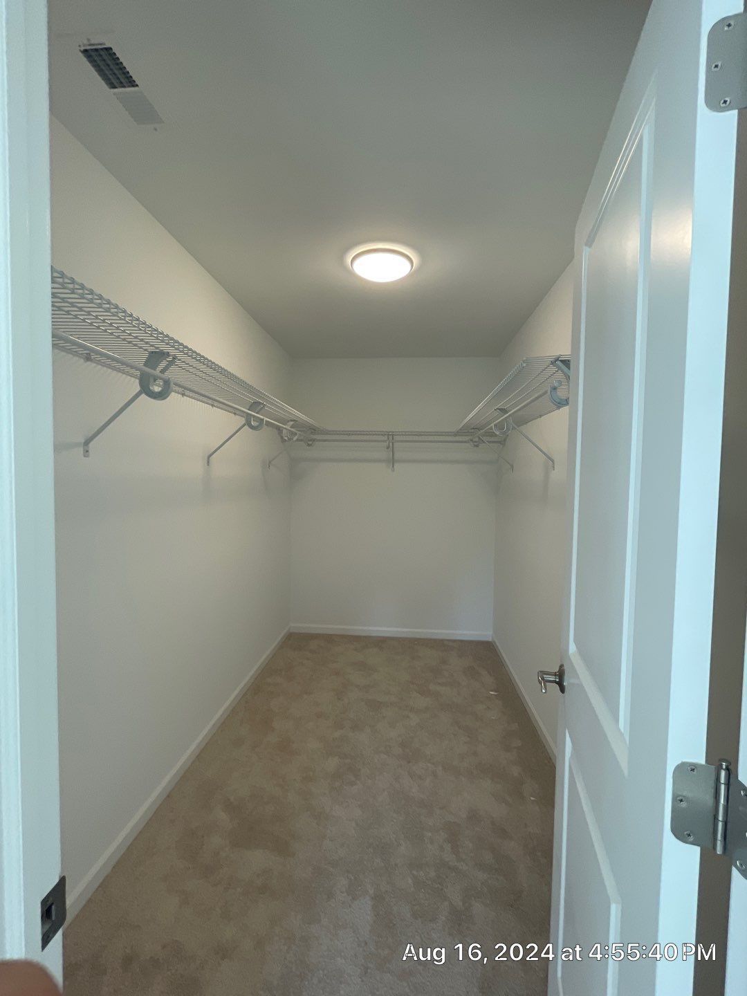 An empty walk in closet in a house with a light on the ceiling.