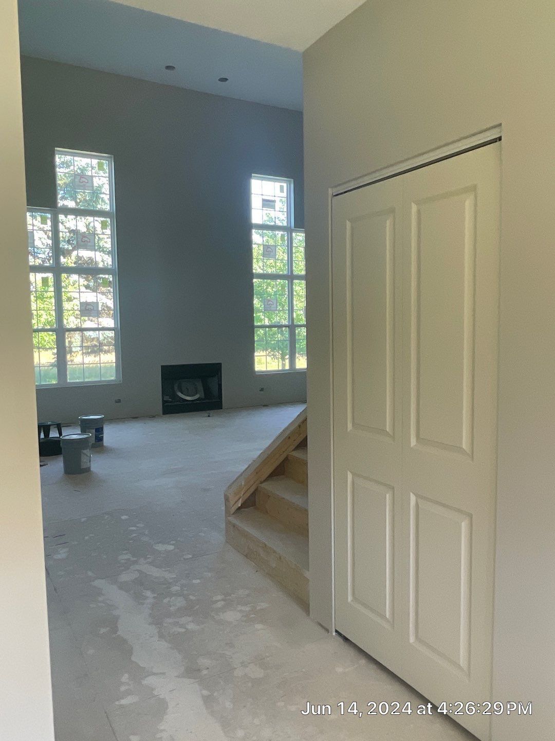 A living room with a fireplace and stairs in a house under construction.