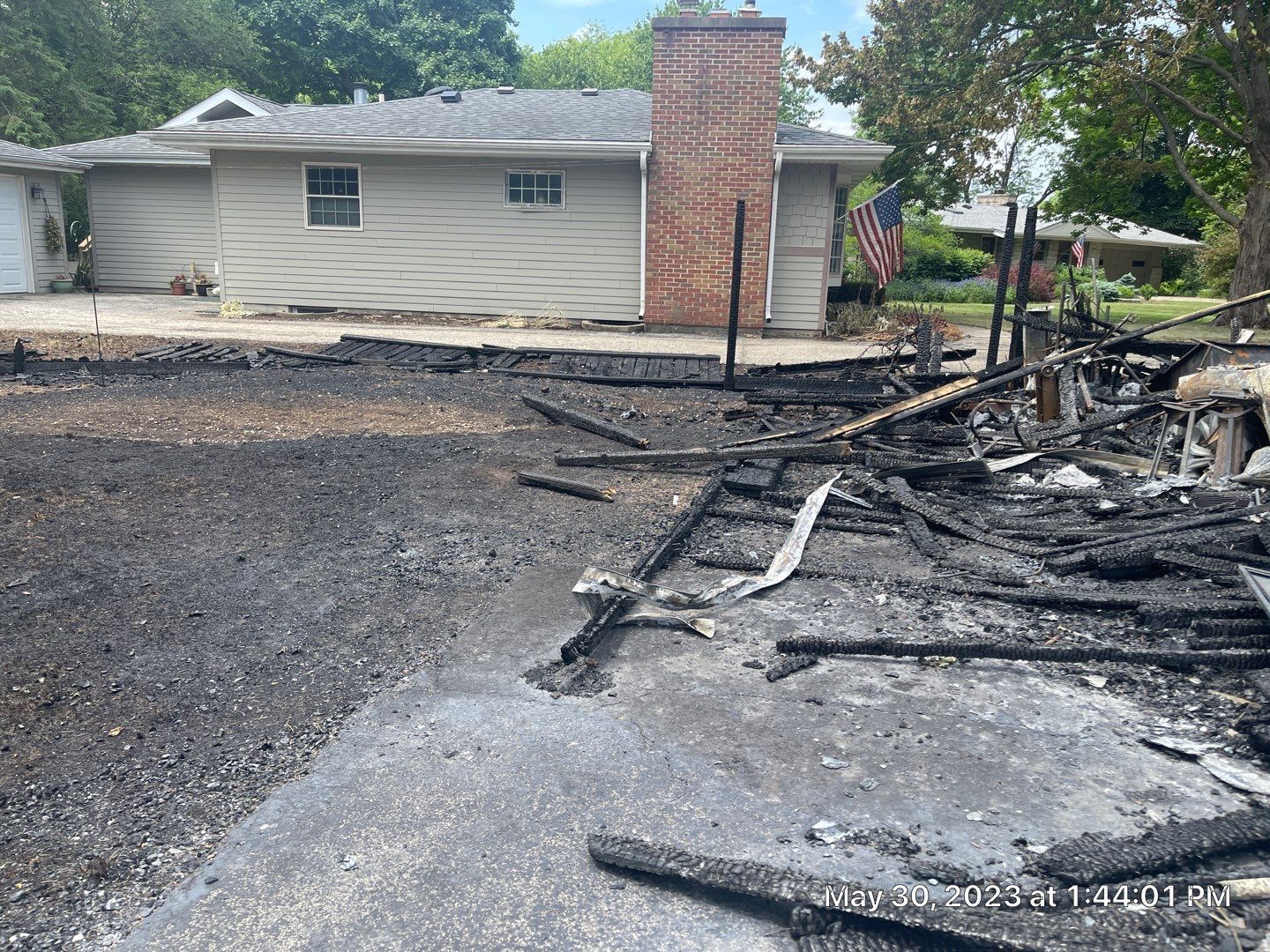 A house that has been damaged by a fire is sitting in the middle of a dirt field.