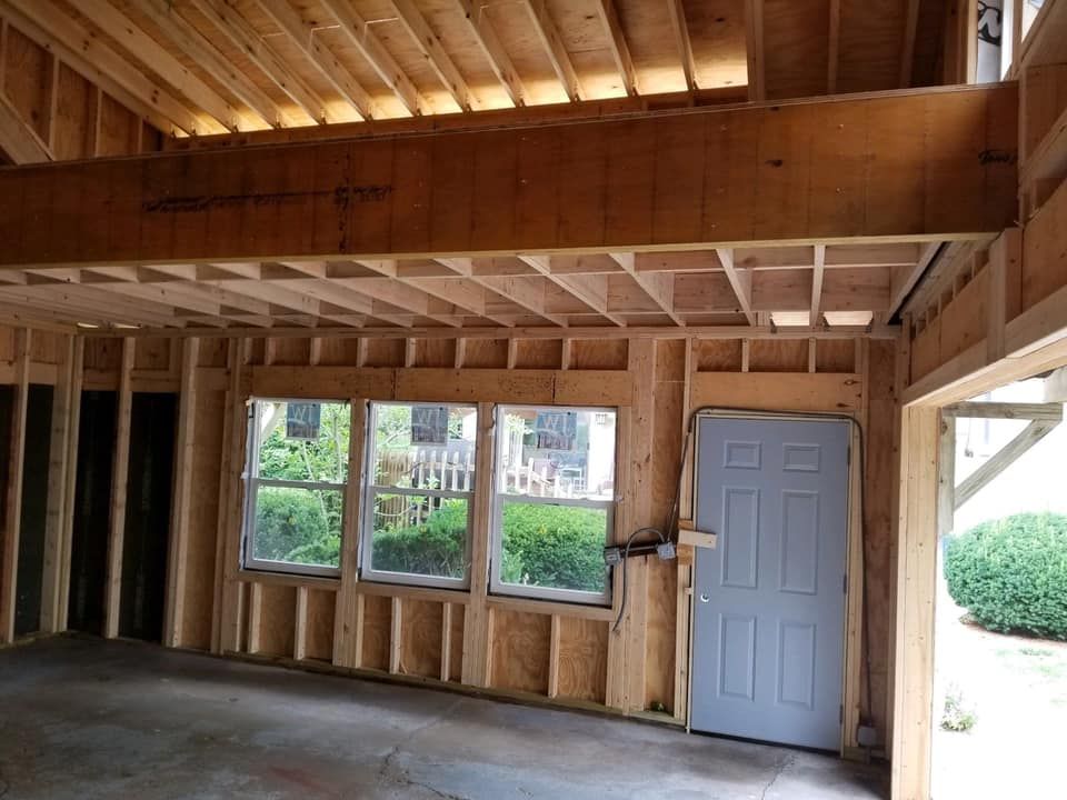 The inside of a garage under construction with a door and windows.