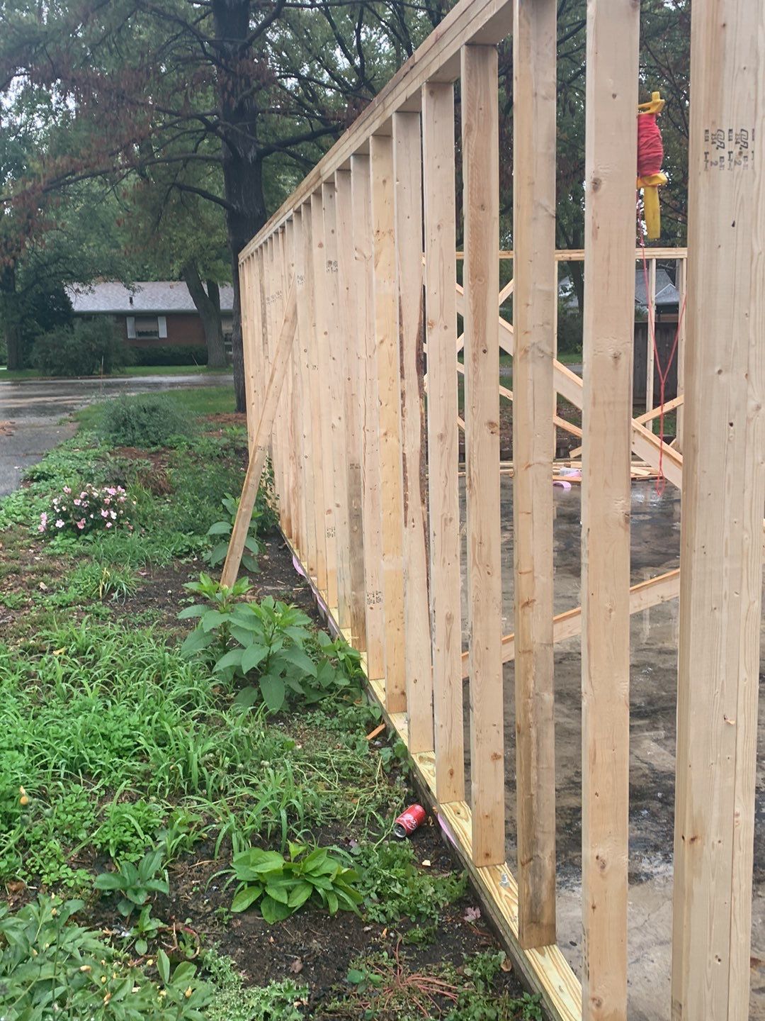 A wooden fence is being built next to a grassy field.