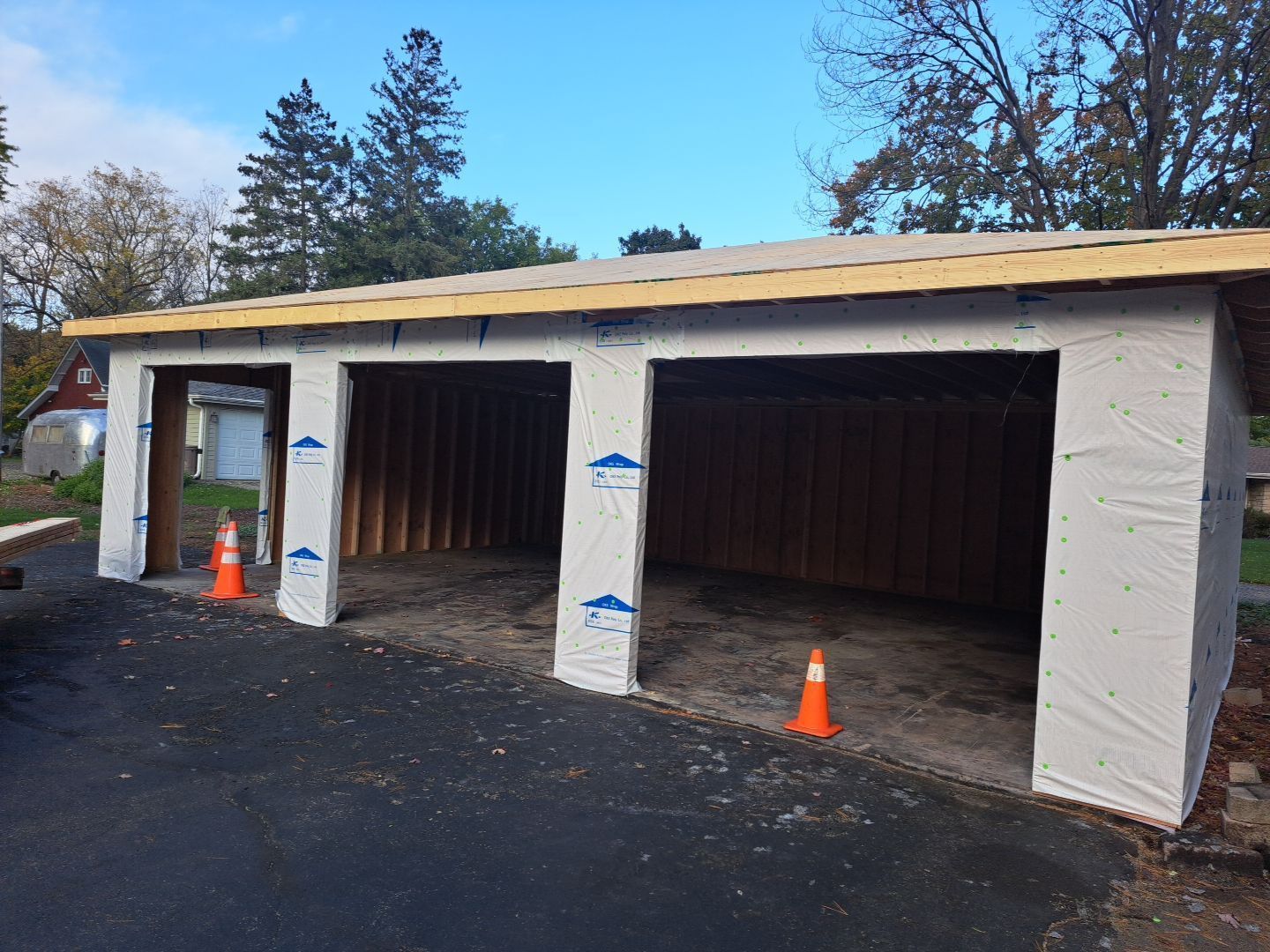 A garage is being built in a driveway with orange cones in front of it.