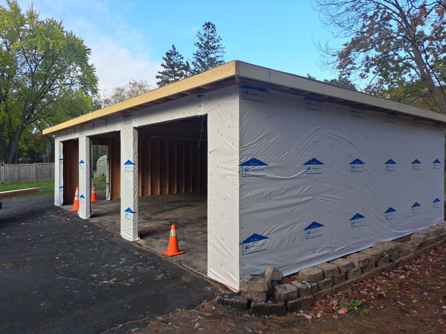 A garage is being built in a driveway with cones on the ground.
