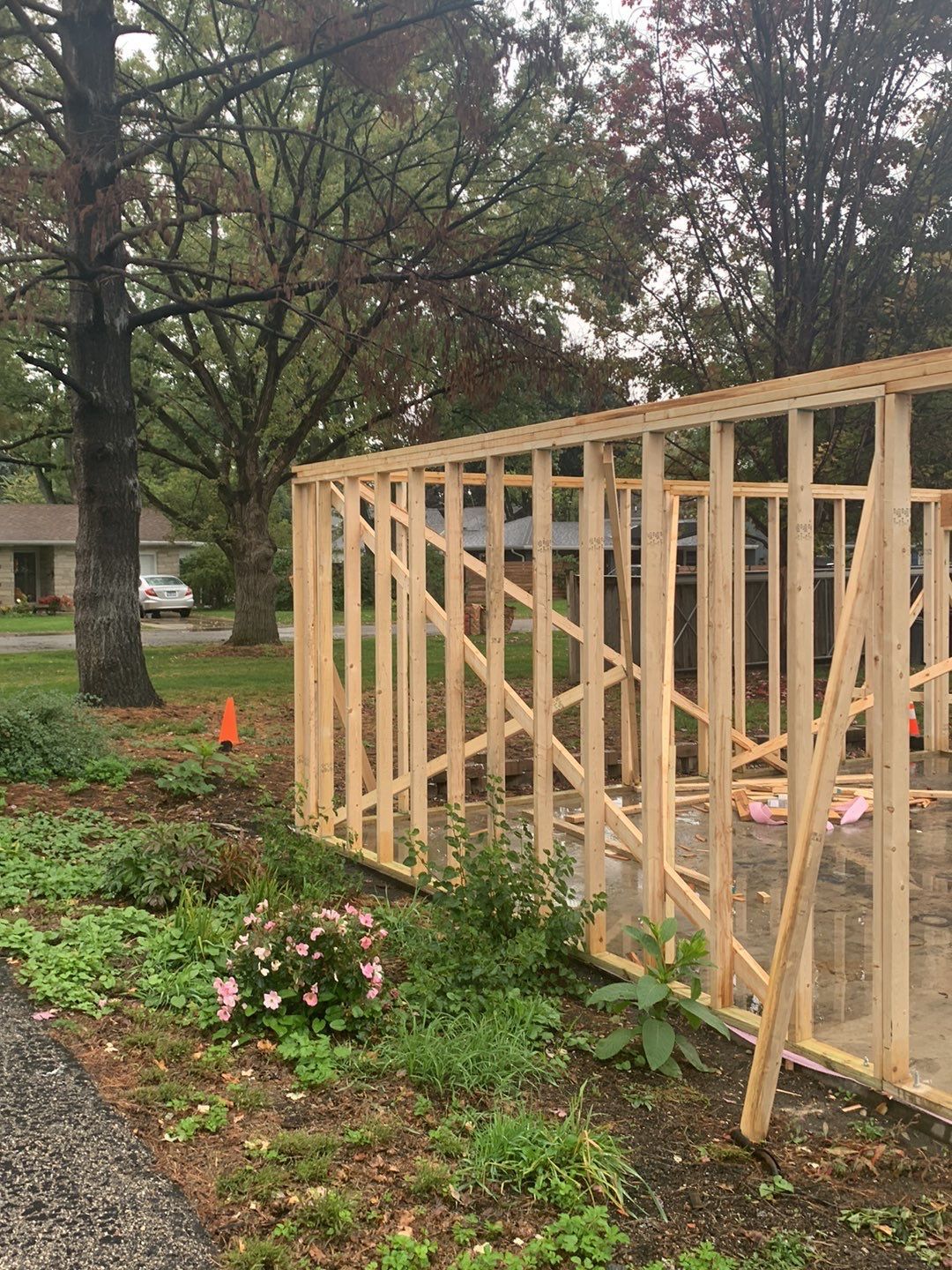 A wooden fence is being built in the backyard of a house.