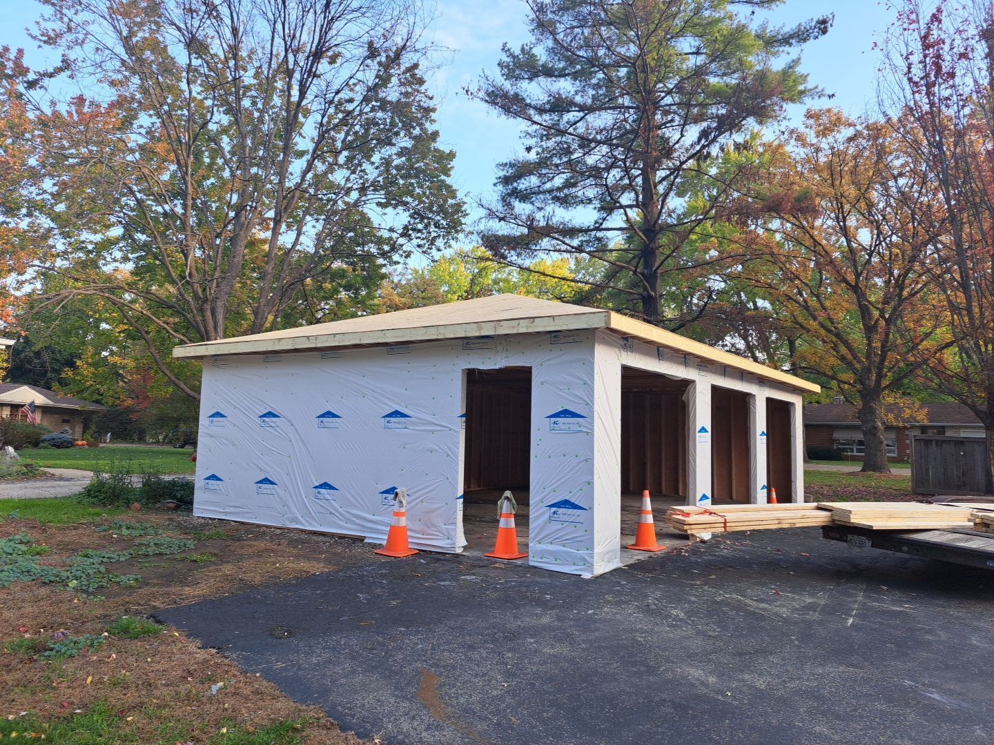 A garage is being built in a driveway with cones in front of it.