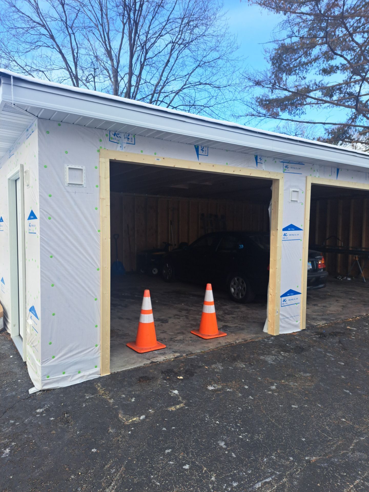 A car is parked in a garage with two orange cones in front of it.