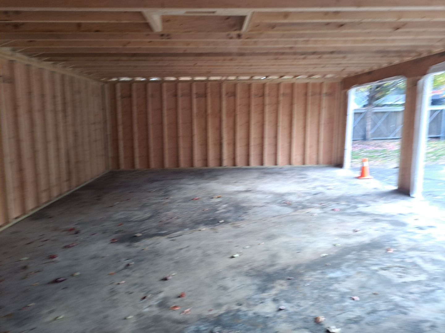An empty garage with wooden walls and a concrete floor.