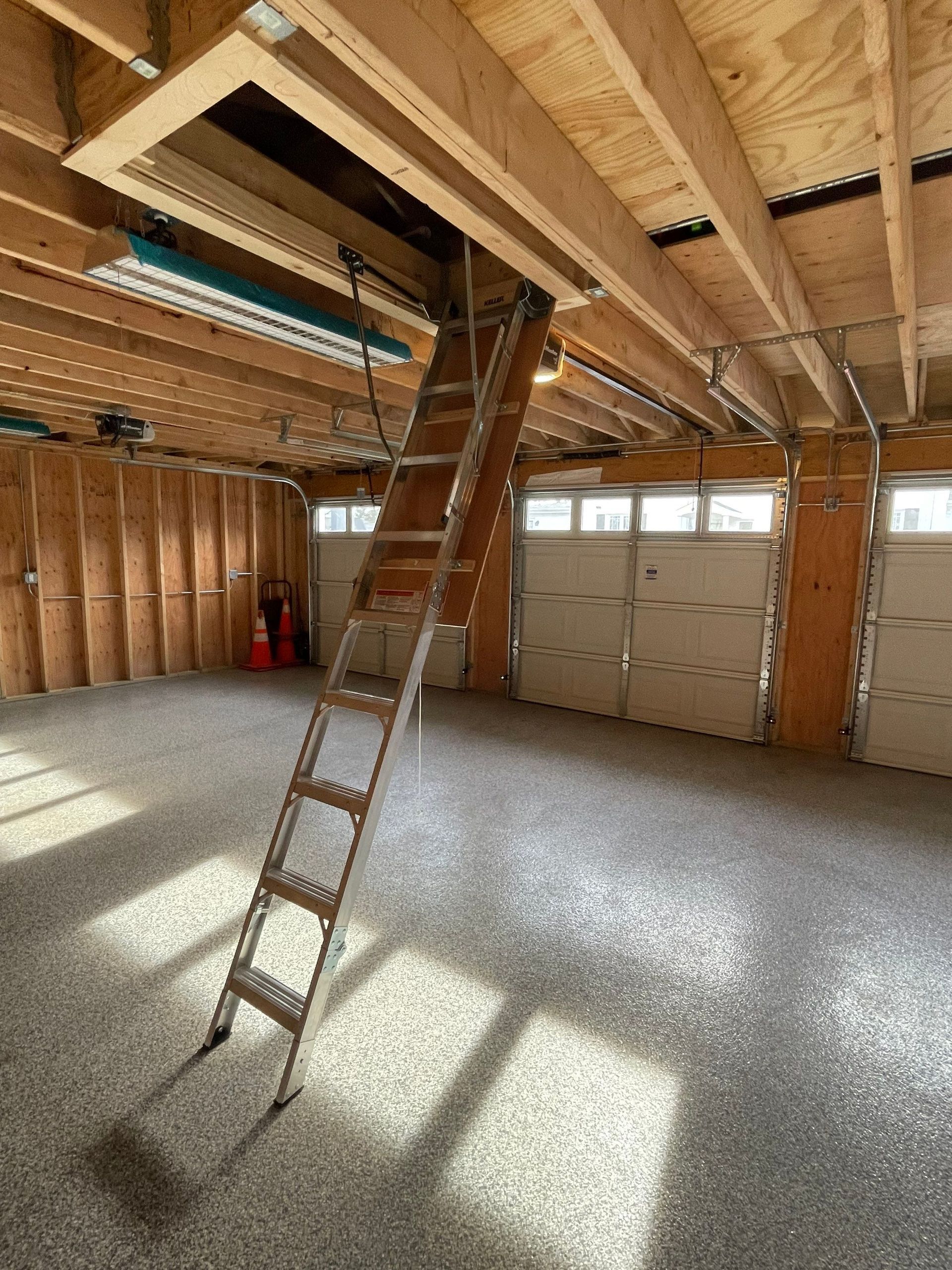A garage with a ladder leading up to the attic.