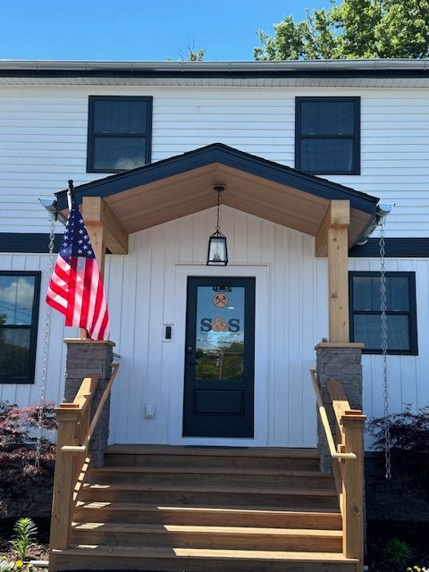 A white house with a black door that says s & s on it