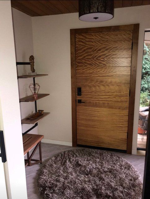 A room with a wooden door and a rug in front of it.