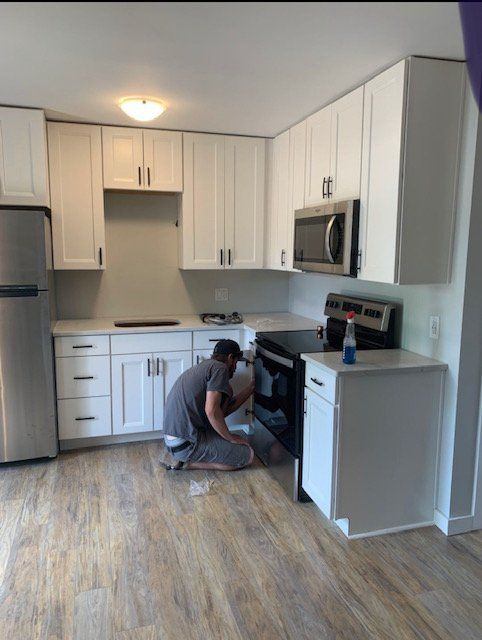 A man is working on a stove in a kitchen