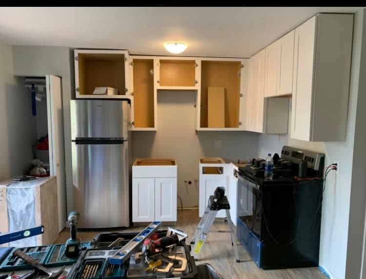 A kitchen is being remodeled with stainless steel appliances and white cabinets.