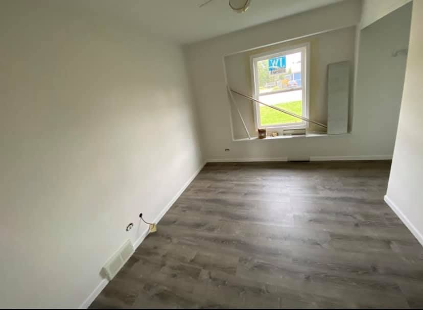 An empty room with hardwood floors and a window.