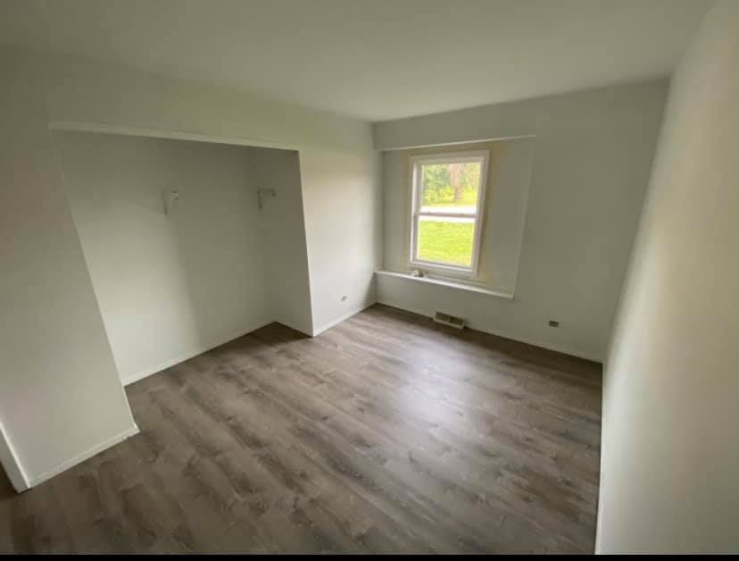 An empty room with hardwood floors and a window.