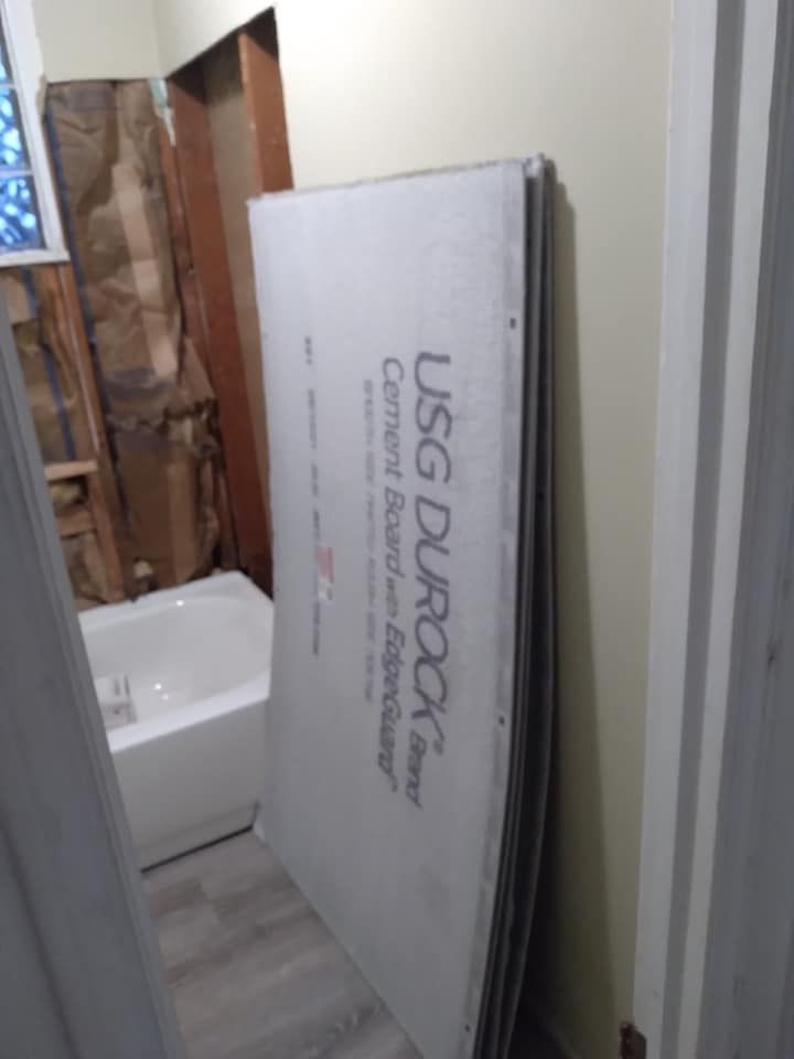 A large piece of styrofoam is sitting in a bathroom next to a bathtub.