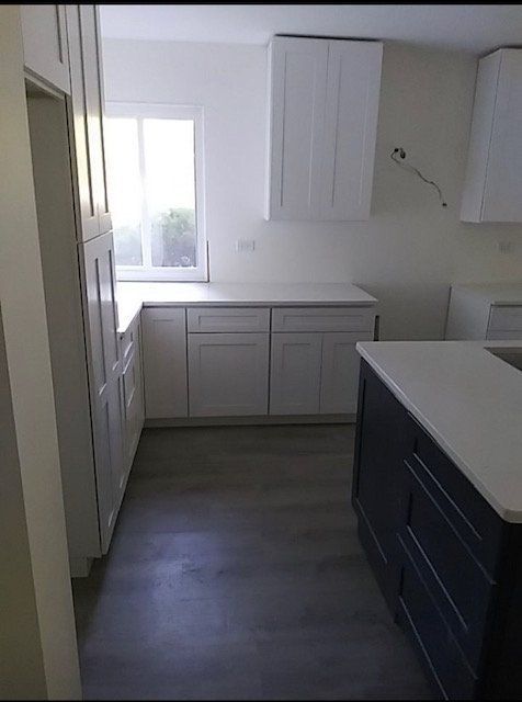A kitchen with white cabinets and a black island.