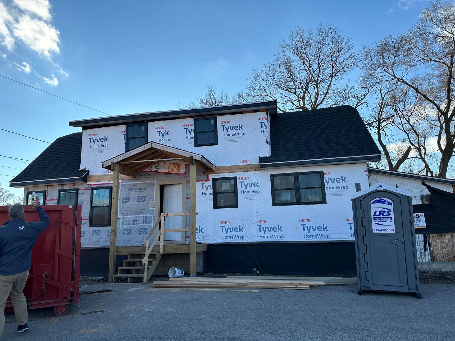 A man is standing in front of a house that is being built.