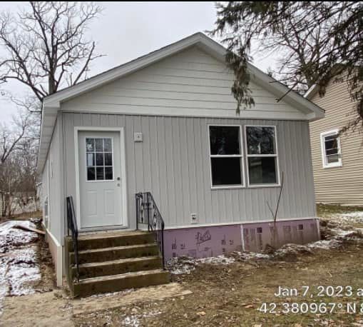 A small white house with stairs leading up to the front door.