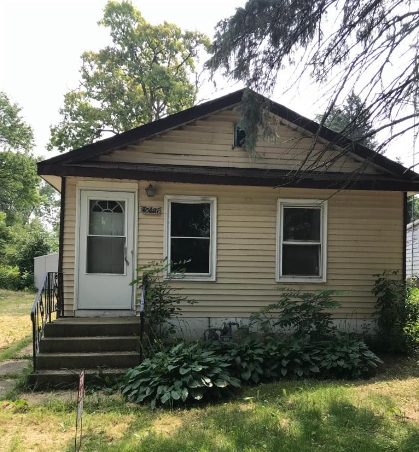 A small house with a brown roof and a white door