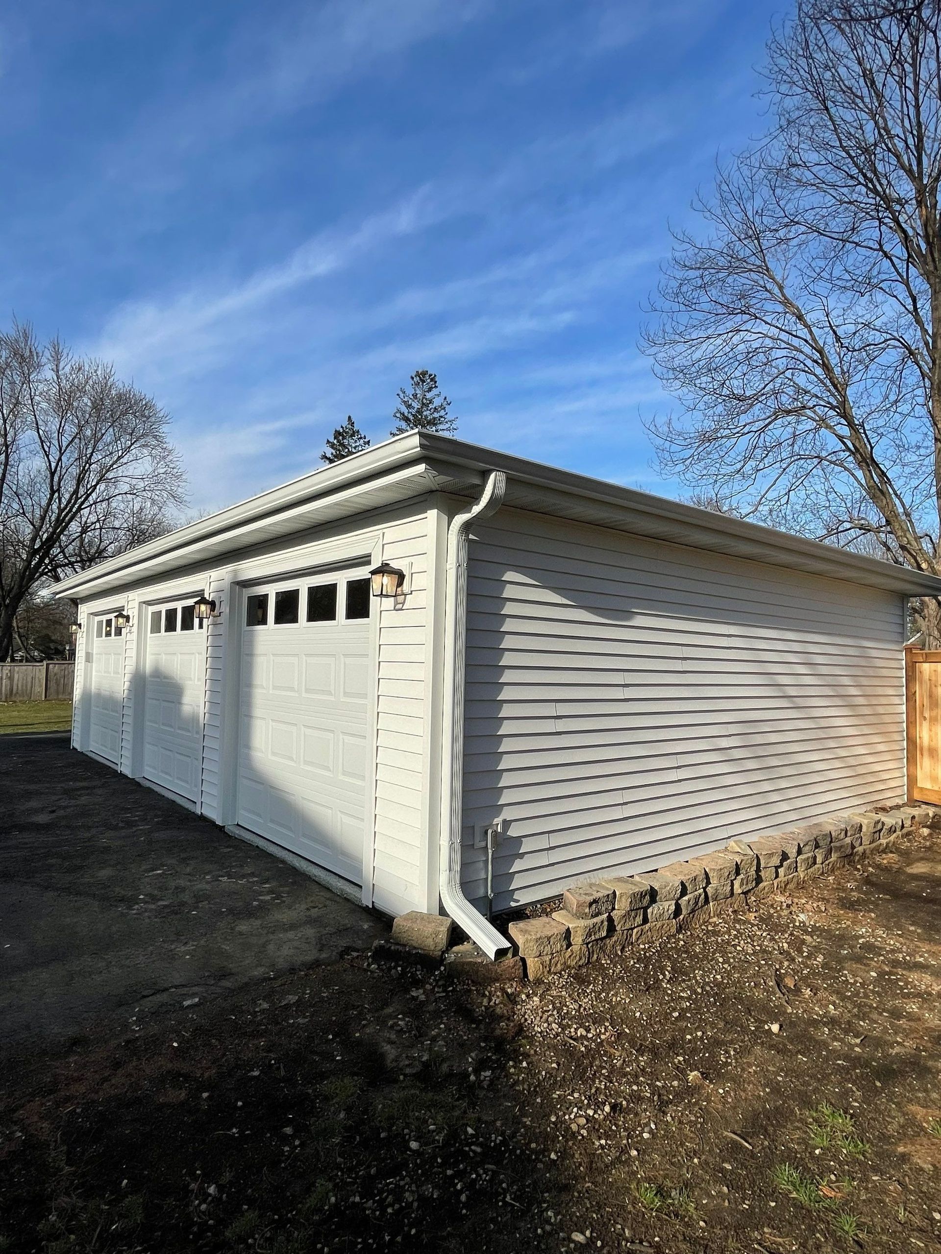 A white garage with three doors and a blue sky in the background.