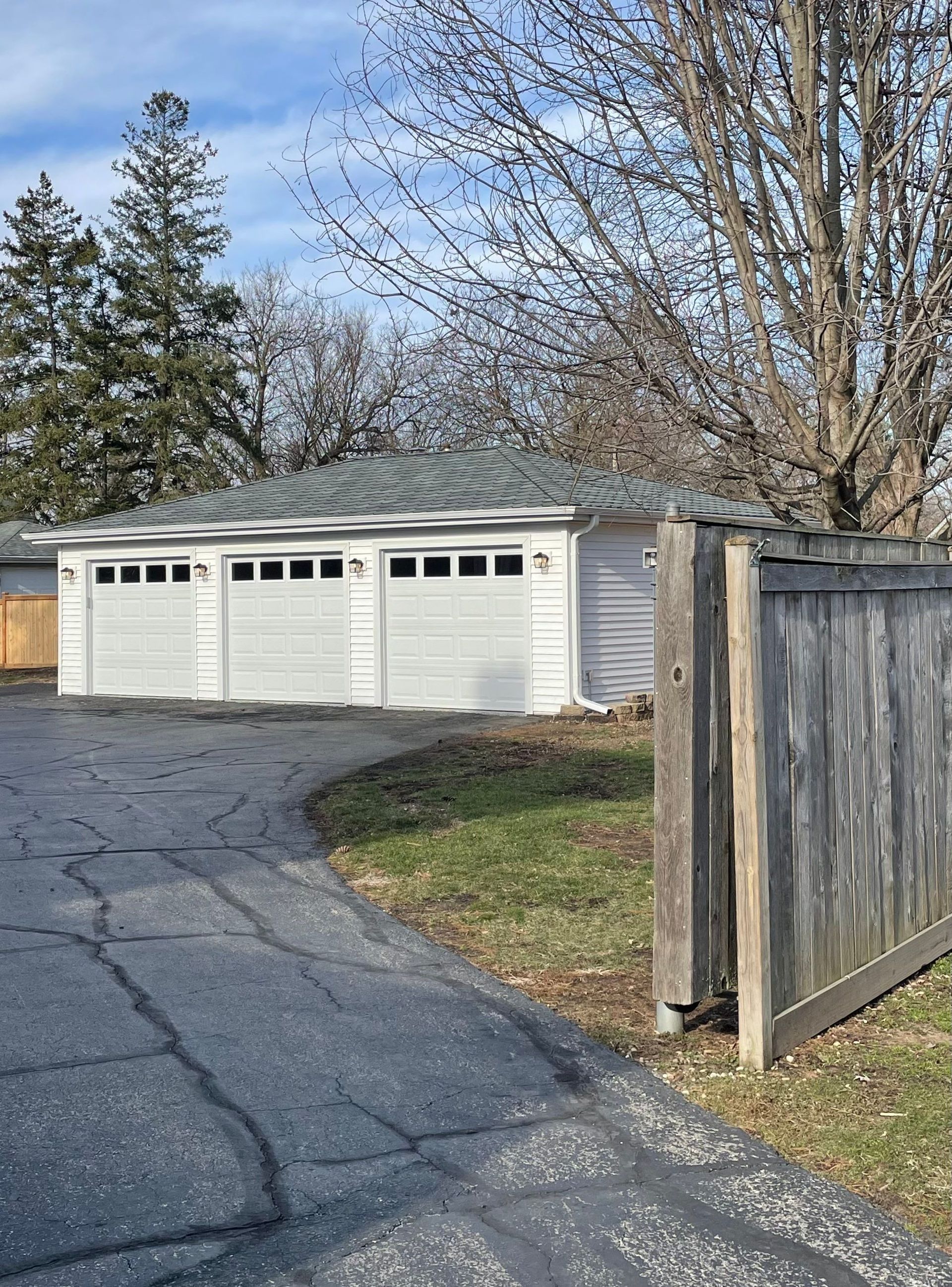 A white garage with a wooden fence in front of it.
