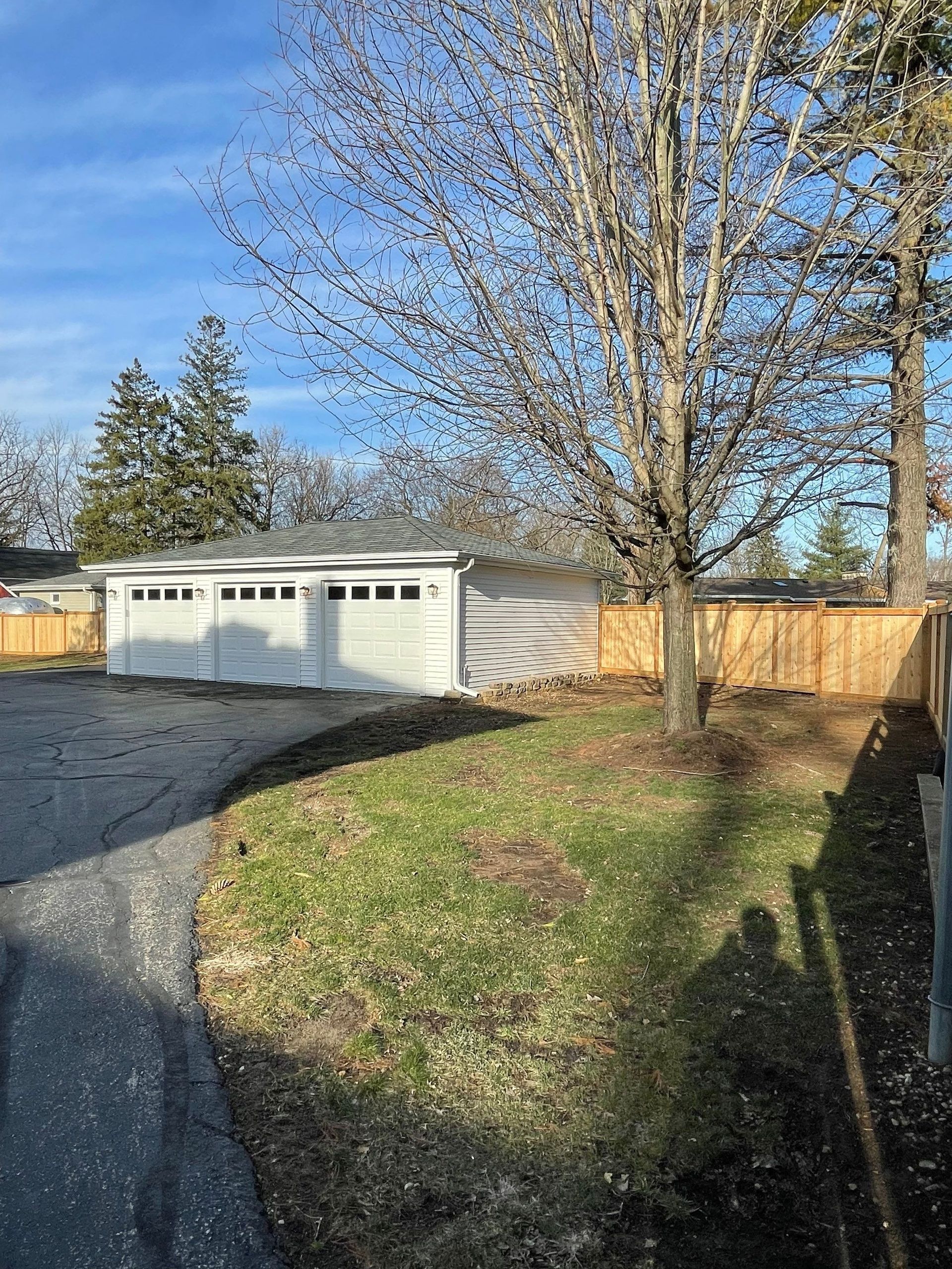 A white garage door is sitting next to a wooden fence.