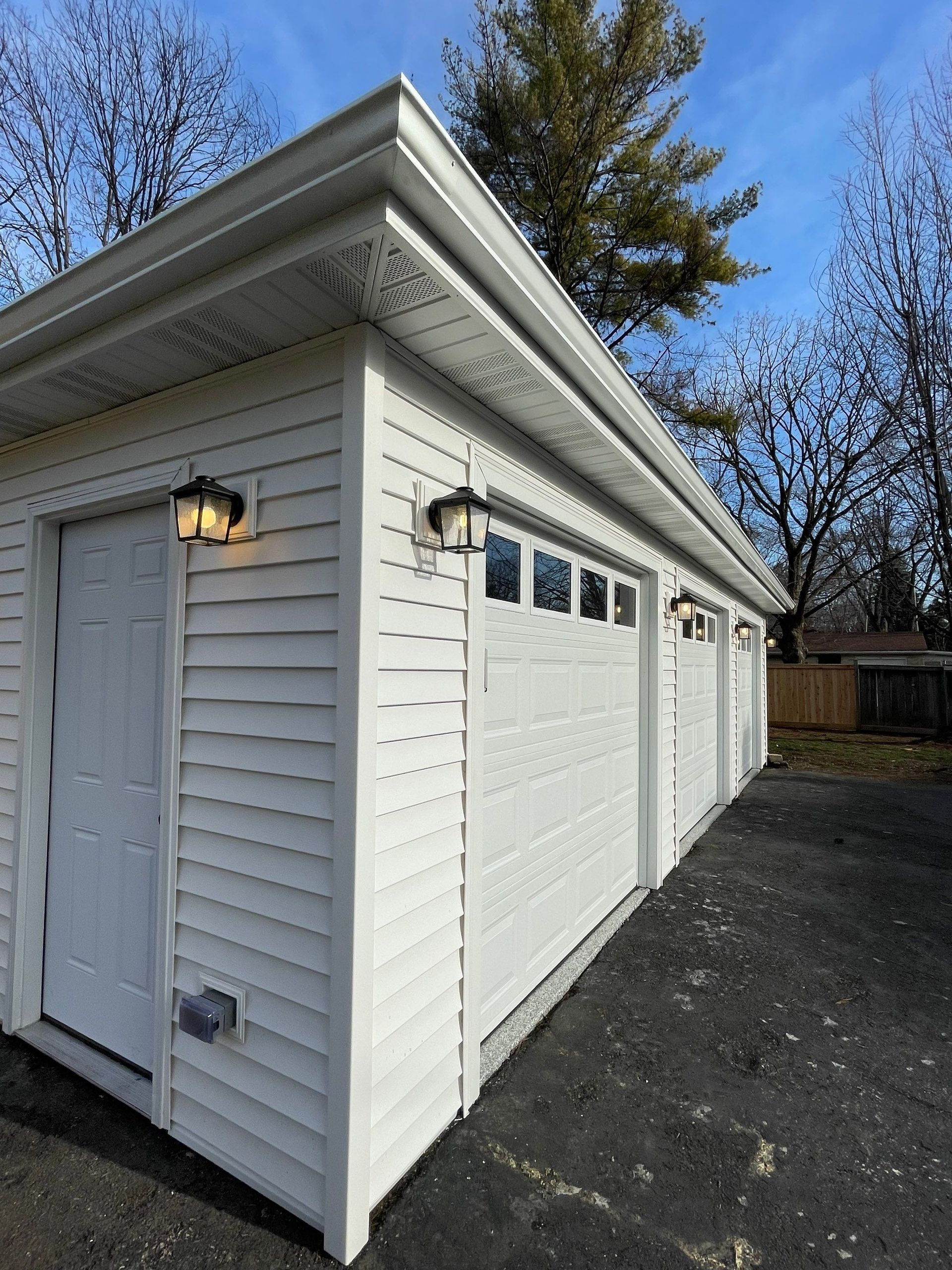 A white garage with three doors and a roof.