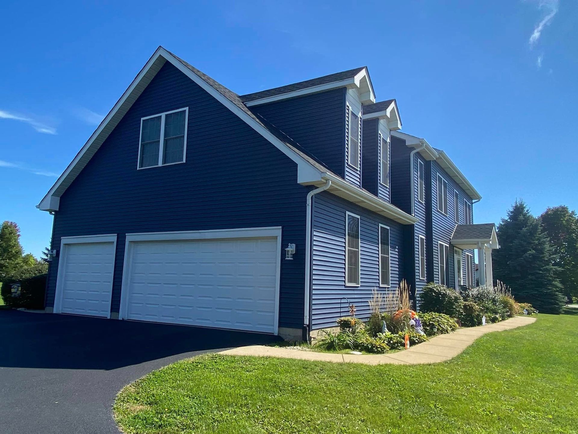 A large house with a blue siding and white garage doors