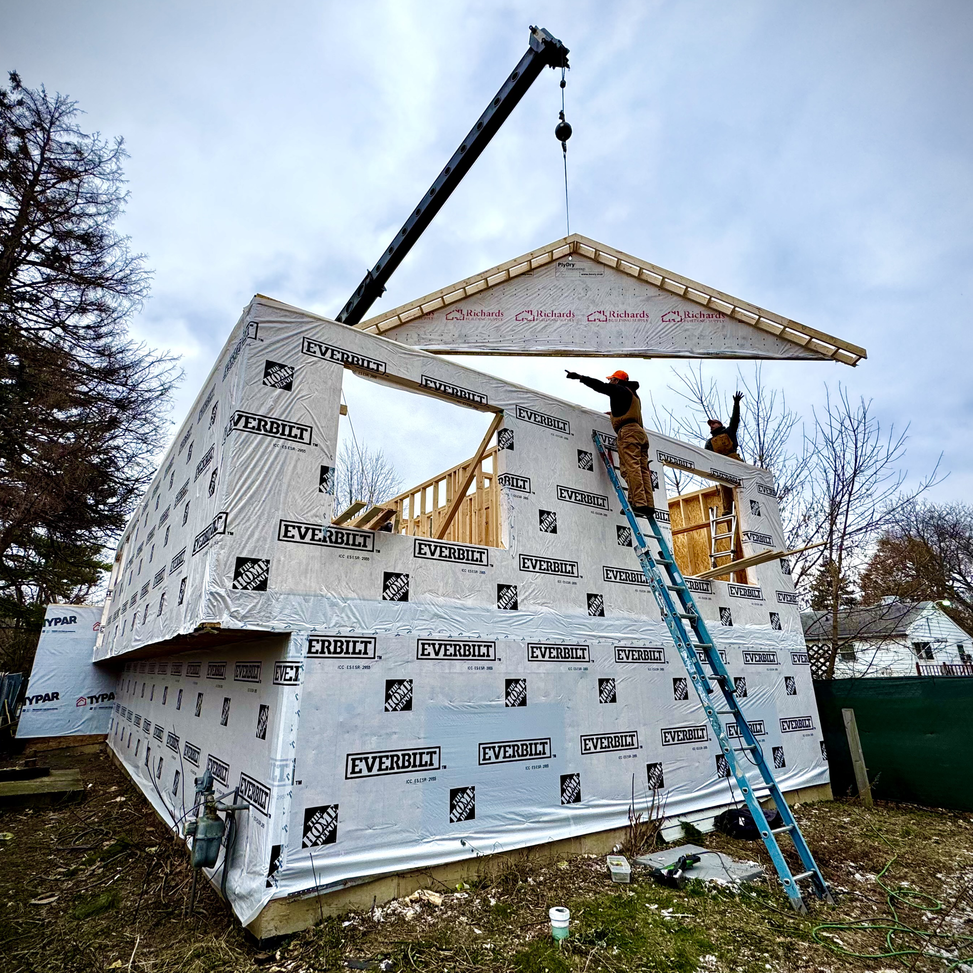 A house is being built with a crane and a ladder.