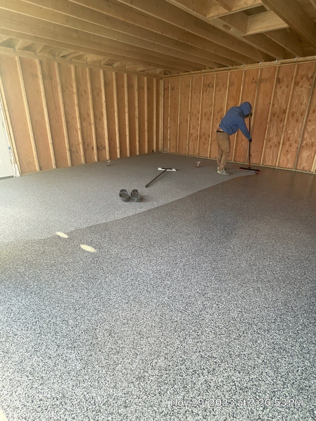 A man is cleaning a garage floor with a broom.