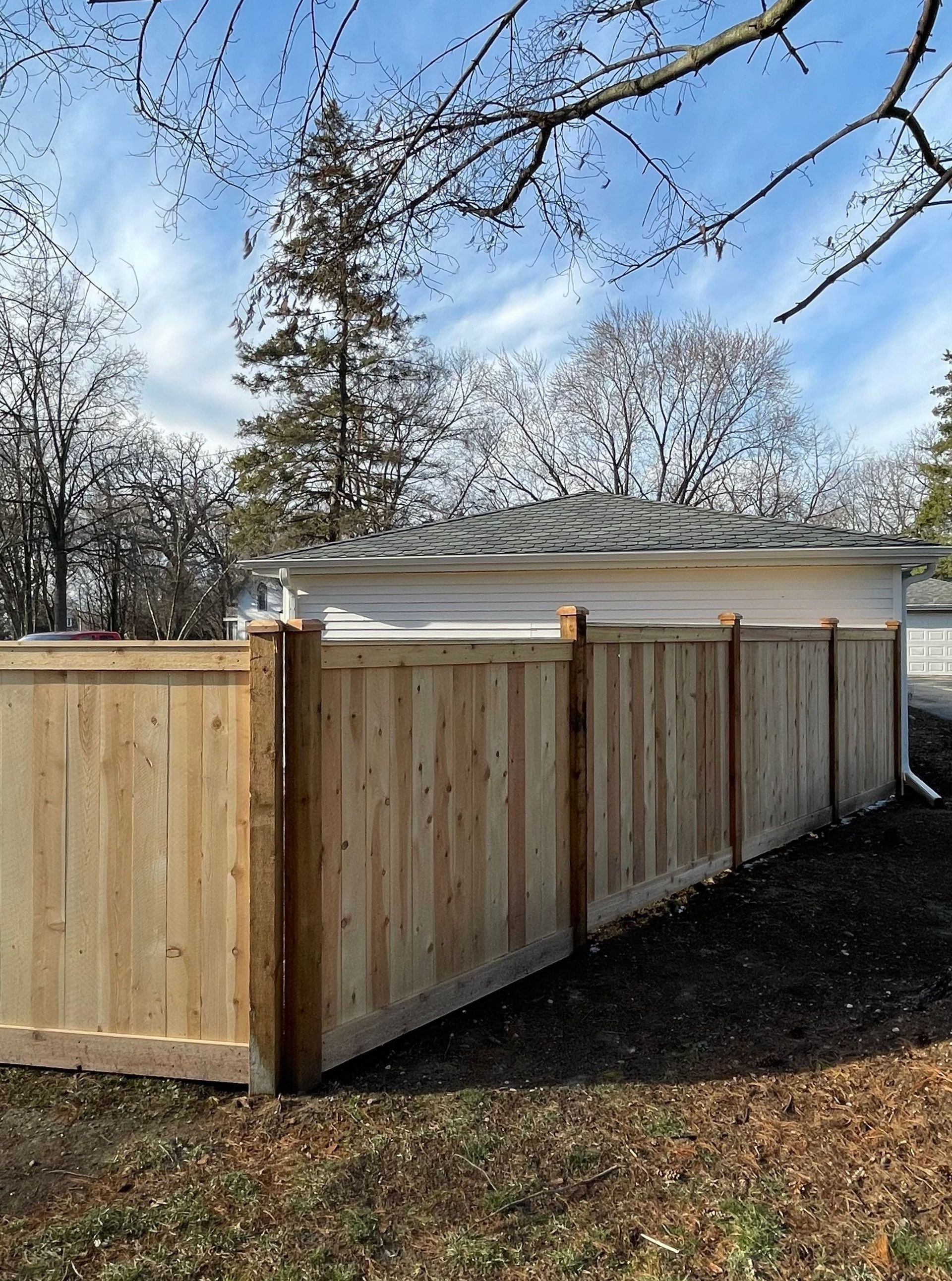 A wooden fence is in the backyard of a house.