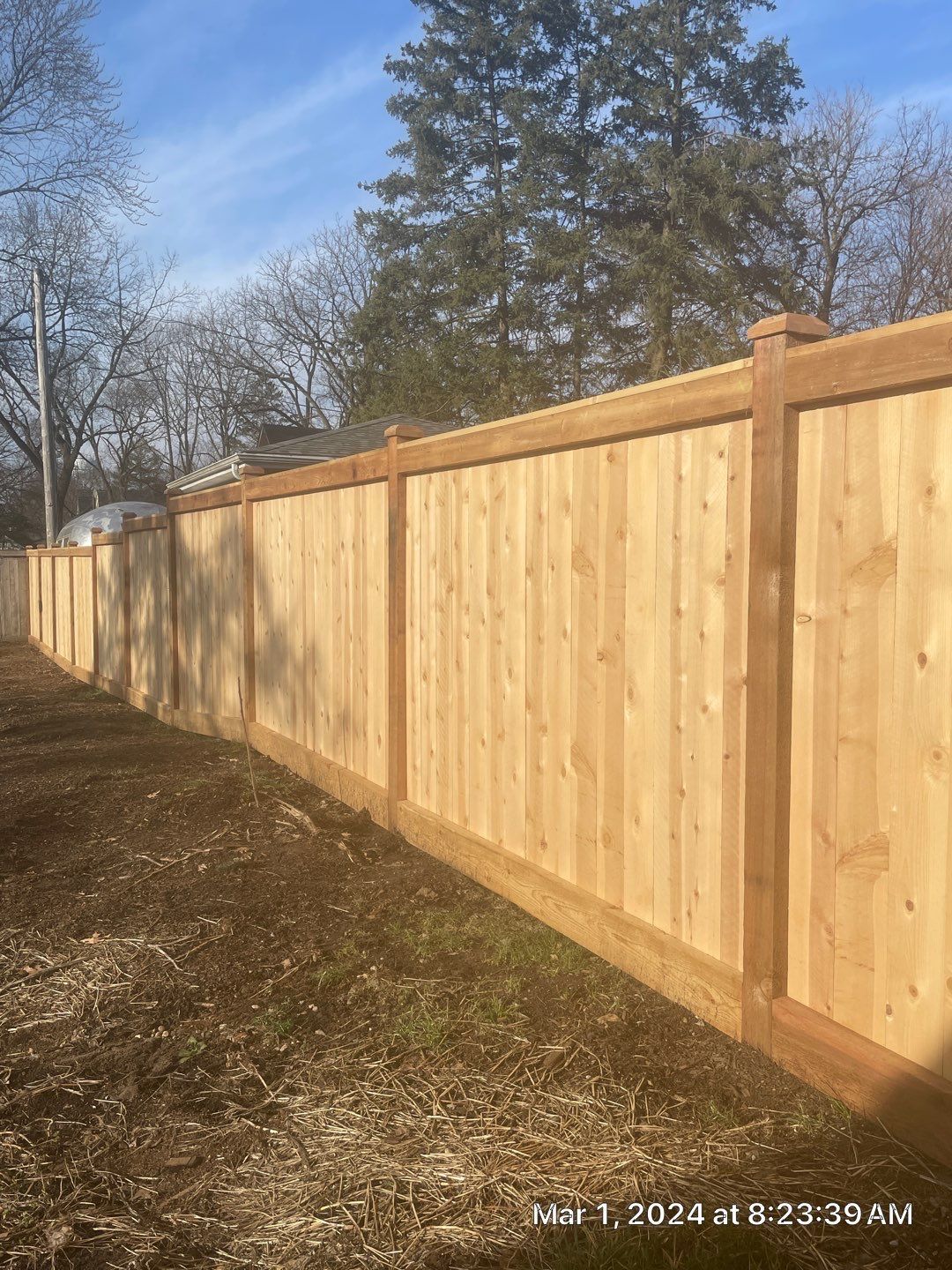 A wooden fence is sitting next to a dirt road.