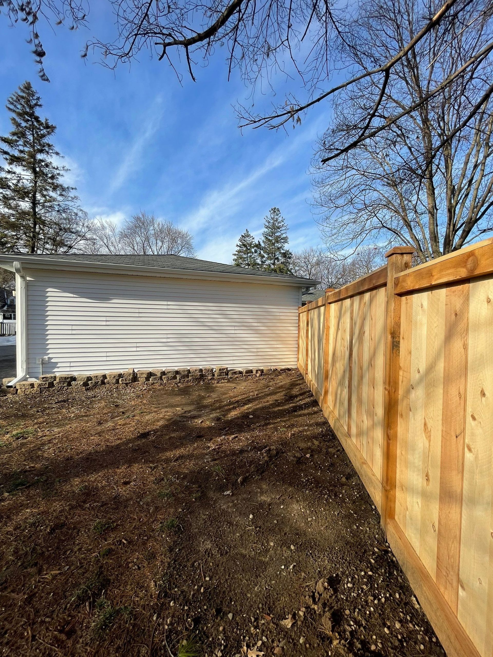A wooden fence is in the backyard of a house.