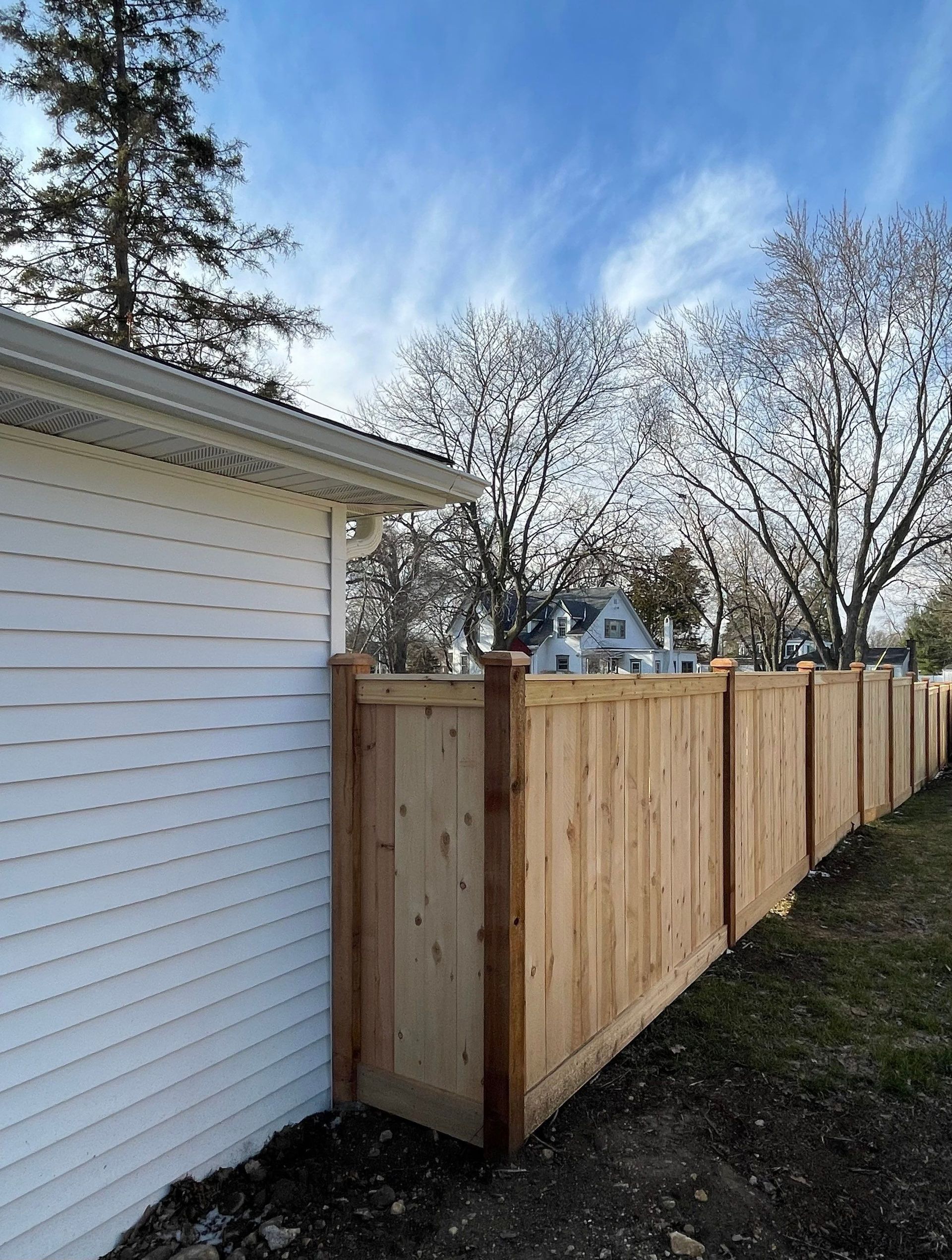 A wooden fence is sitting next to a white house.