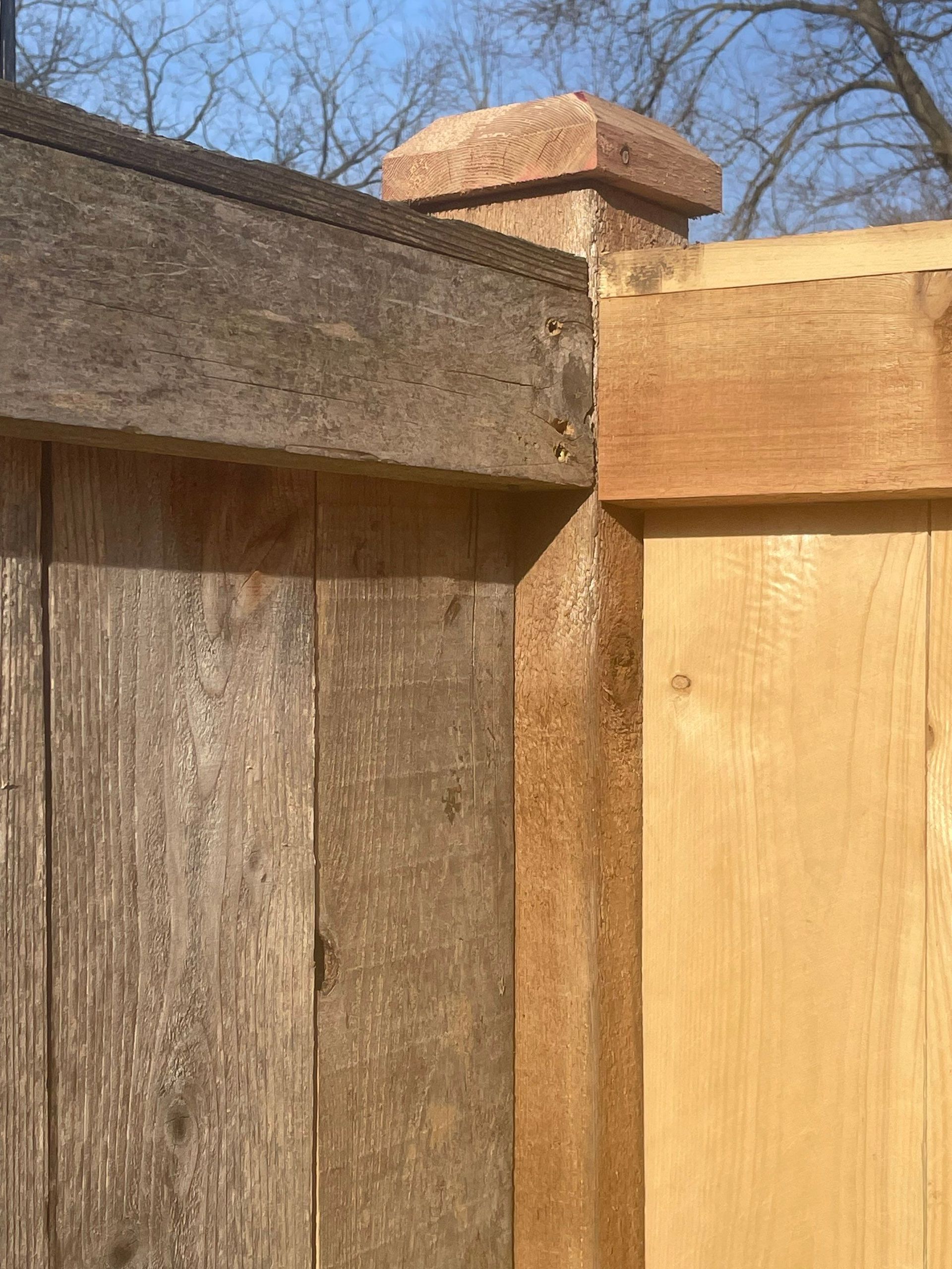 A wooden fence with a brick post on top of it.