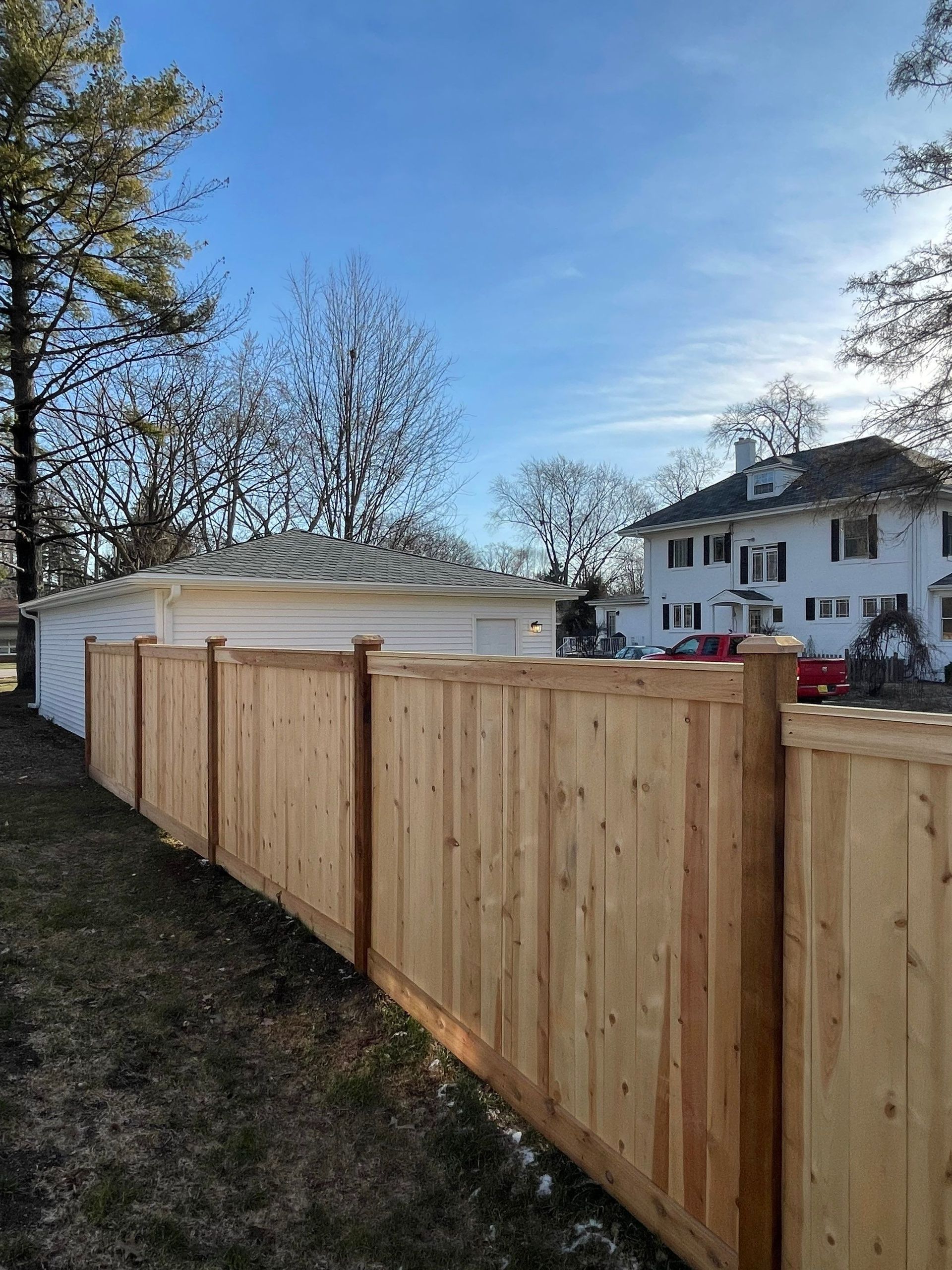 A wooden fence is in the backyard of a house.