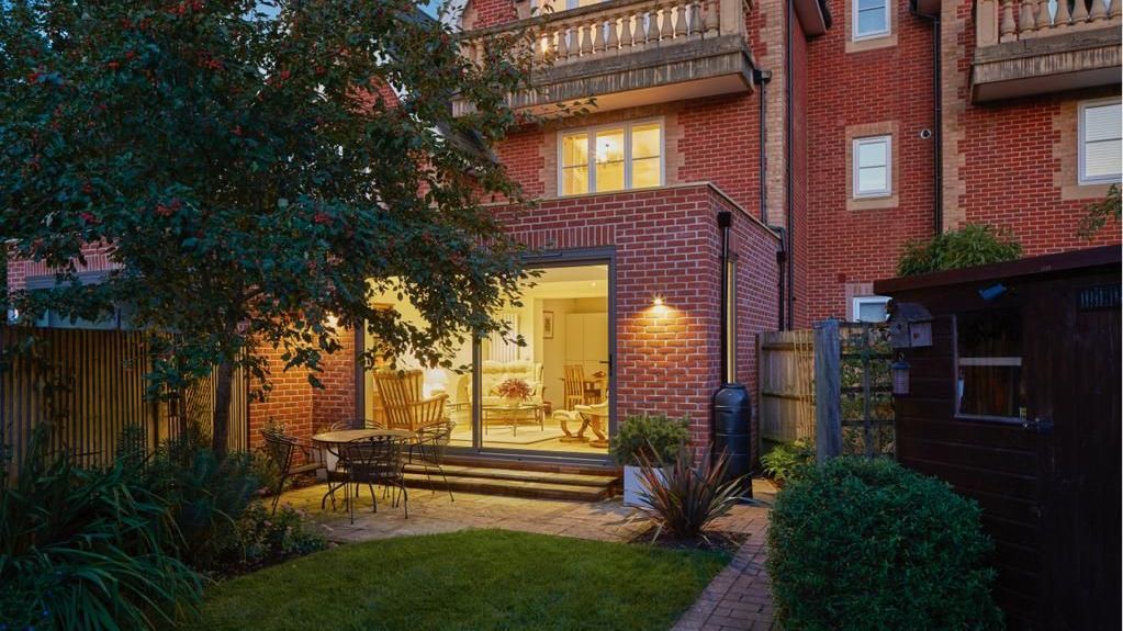 A large brick house with a large sliding glass door is lit up at night.