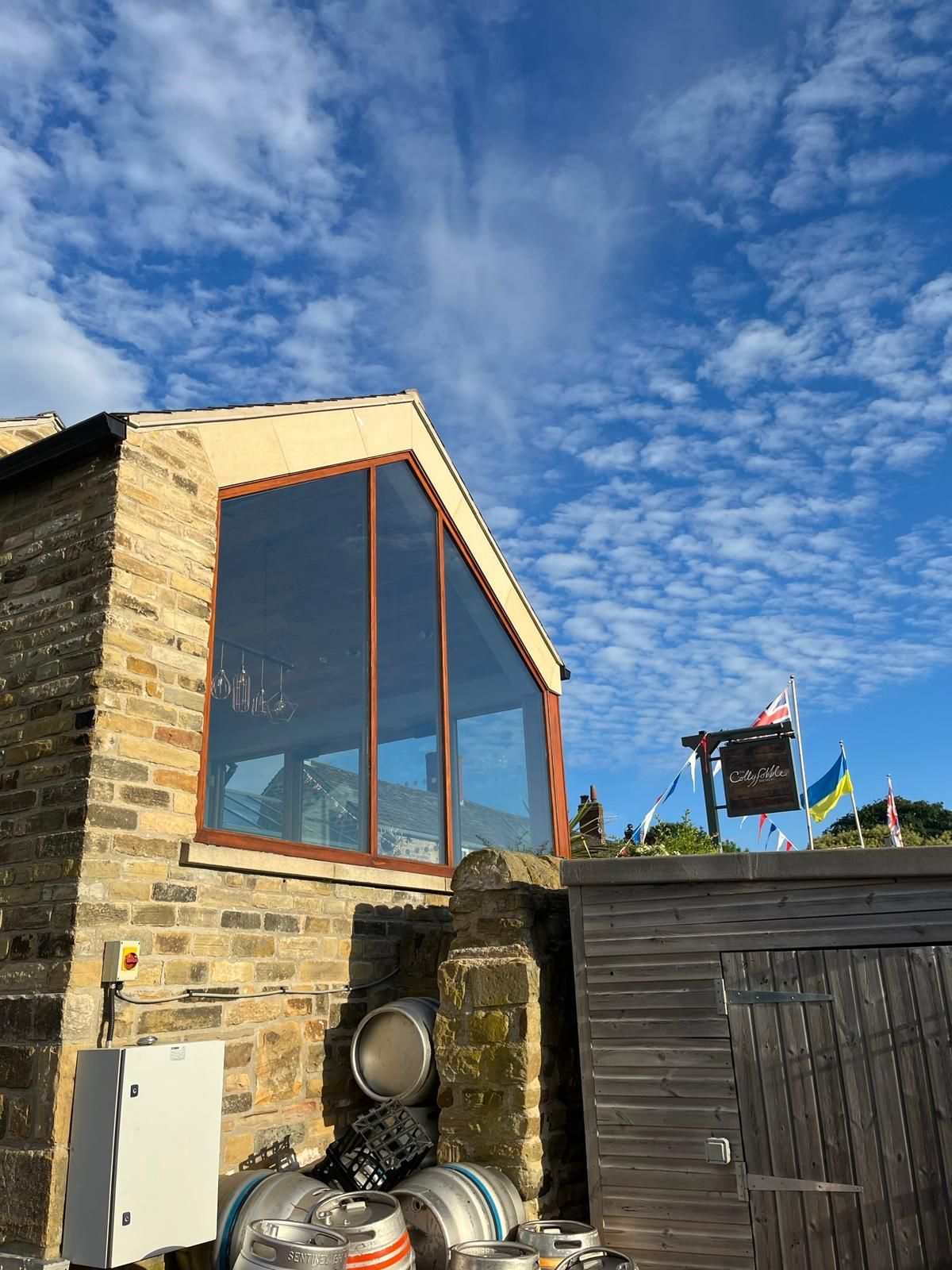 A brick building with a large window and barrels in front of it.